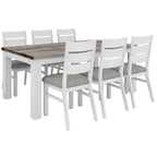 A white dining table with a wooden acacia top and metal handles, accompanied by matching chairs with grey cushions.