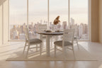 A white round dining table set with four chairs, the table has a multi-colored wooden top and metal legs, the chairs have white backrests and grey seats.